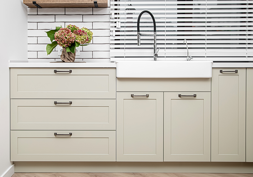 White kitchen furniture near the washbasin in white color in the style of milimalism.